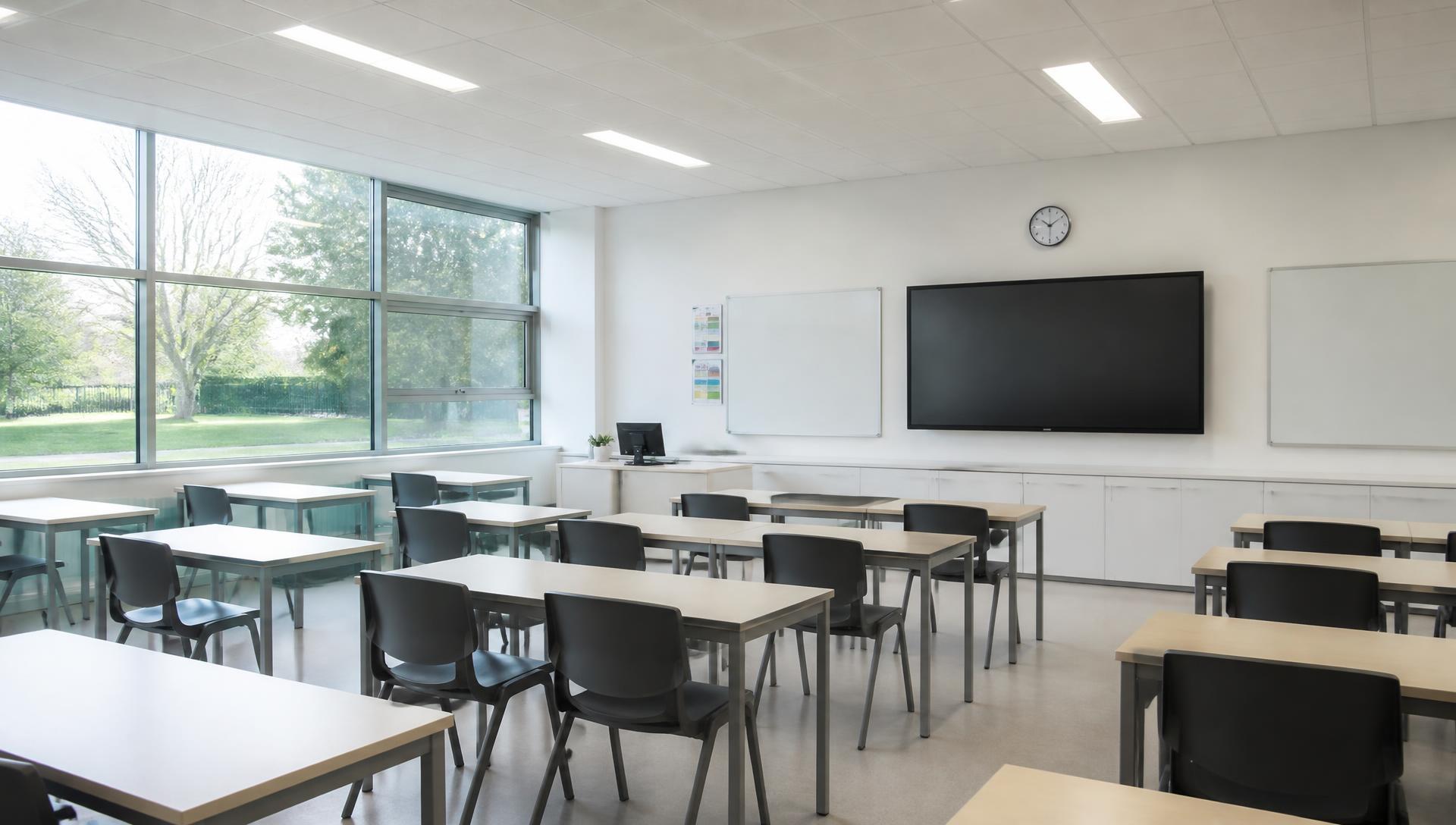 Daylit modern classroom with large windows, empty desks and a calm, uncluttered interior